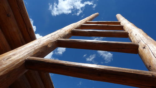 Low angle view of wooden ladder against blue sky