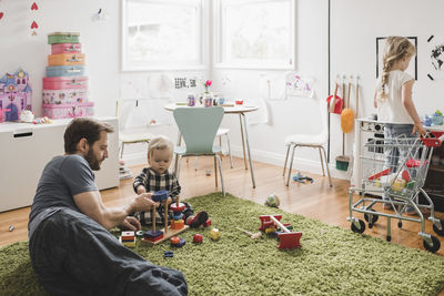 Father and daughters playing with toys in playroom at home