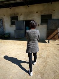 Rear view of woman standing against building