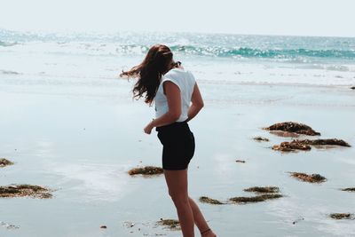 Woman standing at beach against sky