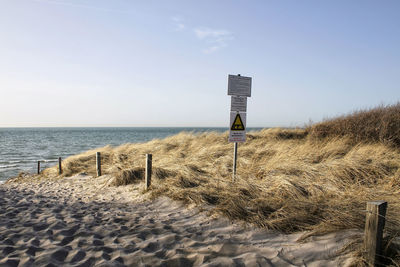 Wooden posts on beach against sky