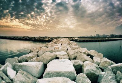 Groyne amidst sea against sky during sunset