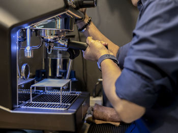 Cropped hands of barista preparing coffee in cafe