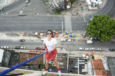 Caucasian woman wearing hero costume descending a tall building in rappel. salvador bahia brazil.