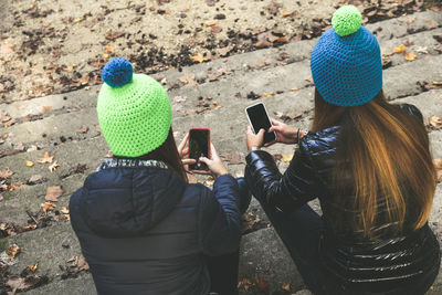 Two girls sitting in the park using smartphone. teen using mobile phone. sisters chat with friends 