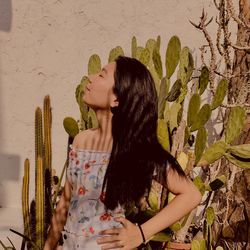 Young woman with eyes closed standing against cactus