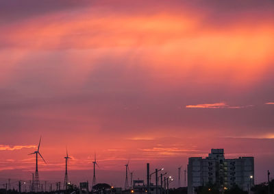 Silhouette buildings against dramatic sky during sunset