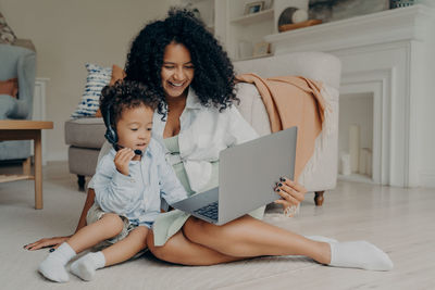 Smiling mother and boy looking at laptop at home