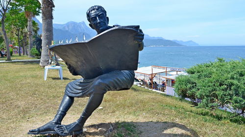 Statue by sea against sky