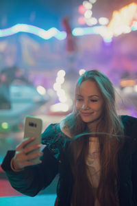 Portrait of smiling young woman using smart phone outdoors
