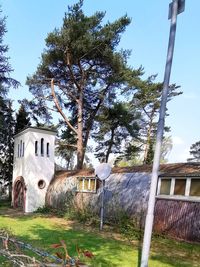 Trees and house on field against sky