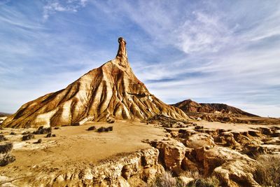 Rock formations on landscape against cloudy sky