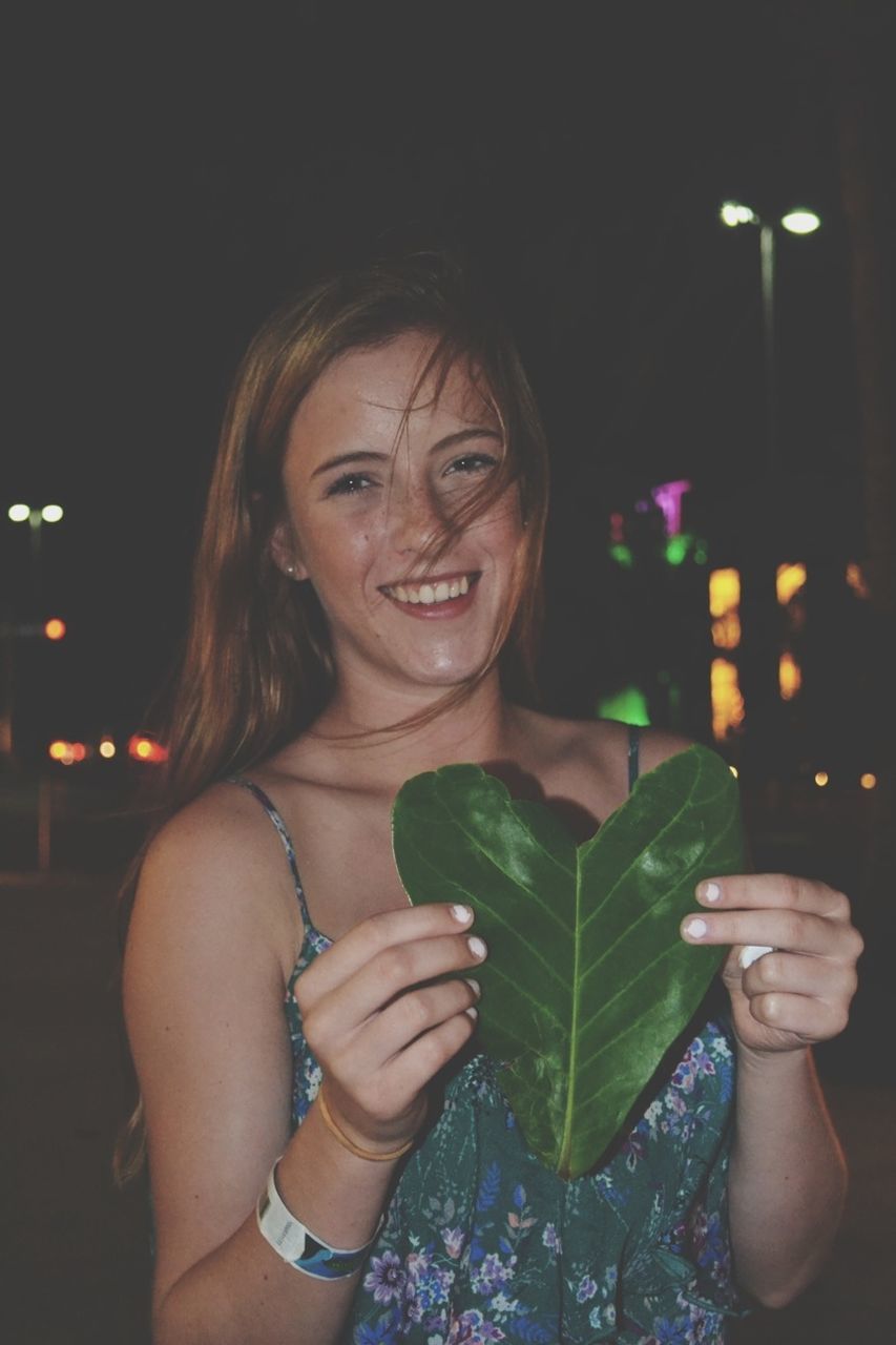 lifestyles, person, leisure activity, night, young adult, young women, portrait, front view, looking at camera, waist up, illuminated, headshot, happiness, holding, casual clothing, smiling, standing, celebration