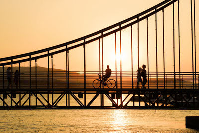 Silhouette people on bridge against sky during sunset