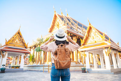 Midsection of woman standing against temple against clear sky