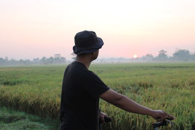 Man standing in field against sky during sunset