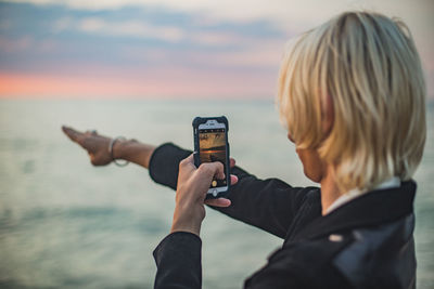 Close-up of boy photographing against sea and sky