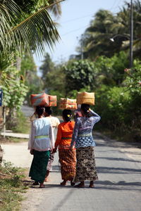Rear view of women with whicker baskets walking on road