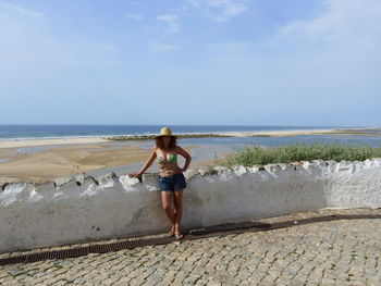 Rear view of boy on beach against sky