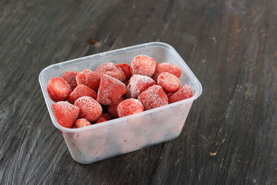 Frozen strawberry in packaging box above wooden table