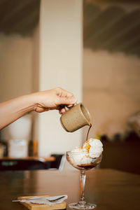 Affogato coffee, hot espresso pouring over ice cream in glass on table.