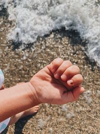 Cropped hand of person with lady bug on water sea 