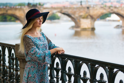 Beautiful woman standing by railing against river