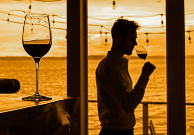 Side view of man drinking wine against sea