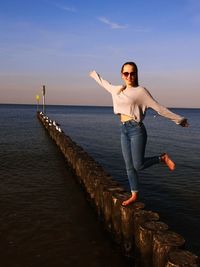 Portrait of young woman standing in sea against sky