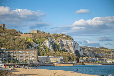 Scenic view of sea by buildings against sky