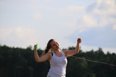 Cheerful woman holding string against sky