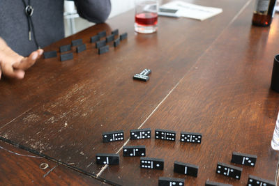 Midsection of man by dominos on wooden table