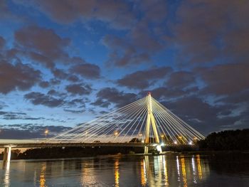 Illuminated bridge over river against sky at dusk