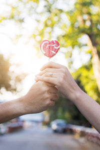 Cropped hands holding heart shape lollipop