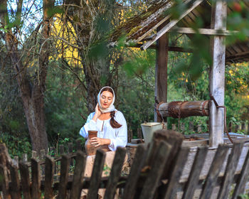 Portrait of young woman standing against trees