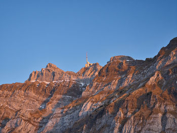 Low angle view of rocky mountains against clear blue sky