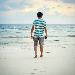 Rear view of man walking at beach