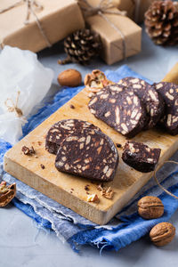 Traditional italian dessert - christmas chocolate salami with broken biscuits and walnuts on a table