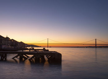 Bridge over calm river at sunset