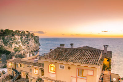 High angle view of houses by sea against sky during sunset