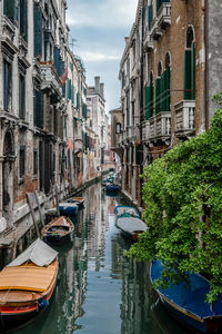 Boats moored in canal amidst buildings in city