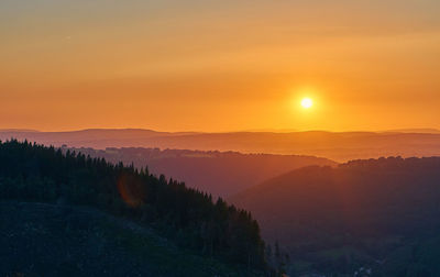 Scenic view of silhouette mountains against orange sky