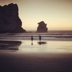 Silhouette people on beach against clear sky