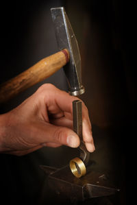 Cropped hand of manual worker hitting metallic ring in factory