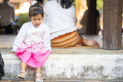 Full length of girl sitting on flooring by tree trunk indoors