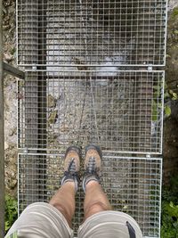 Low section of man standing on metal fence