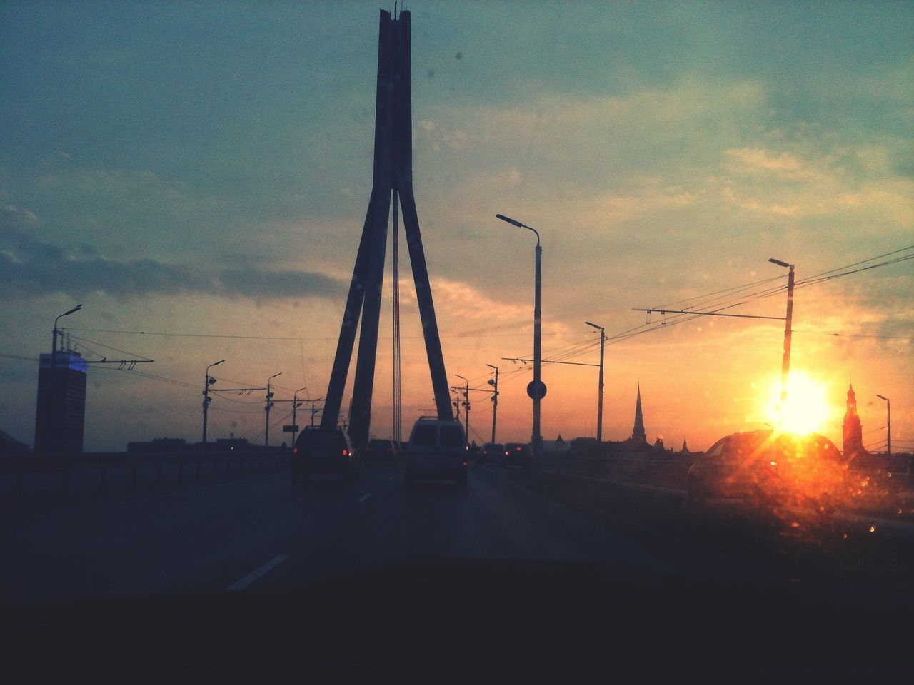 sunset, sun, transportation, sky, orange color, mode of transport, silhouette, cloud - sky, sunlight, nature, sunbeam, beauty in nature, car, lens flare, scenics, land vehicle, outdoors, no people, fuel and power generation, connection