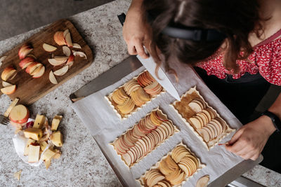 High-view angle of young adult women making pastry with apples