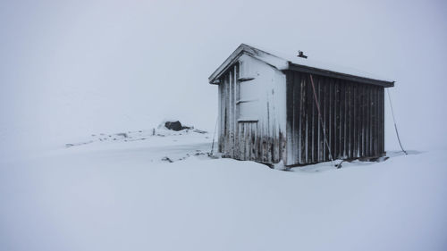 House on snowy field against sky