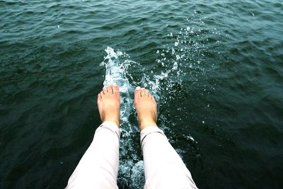 Low section of person splashing water in sea